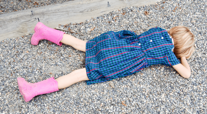 Little girl lays face down on the street throwing a tantrum.