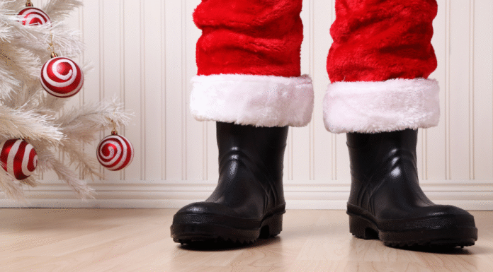 Santa's boots next to a white Christmas tree with red and white ornaments.
