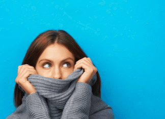 Woman looks embarrassed hiding in her turtleneck.