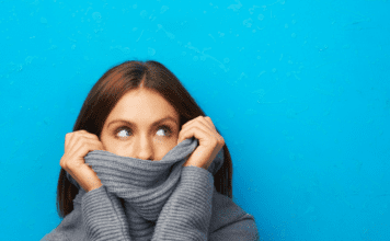 Woman looks embarrassed hiding in her turtleneck.