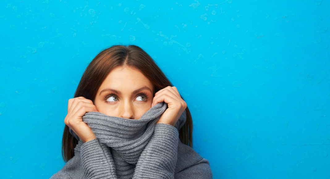 Woman looks embarrassed hiding in her turtleneck.