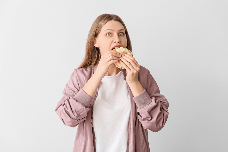 Woman eats a bagel, looking shocked.