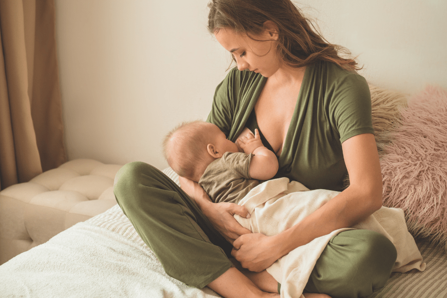 Mother wears nursing-friendly romper while breastfeeding her baby.