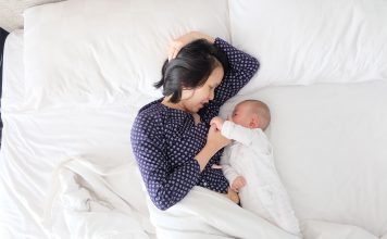 Mother has breastfeeding struggles while laying in bed with baby.