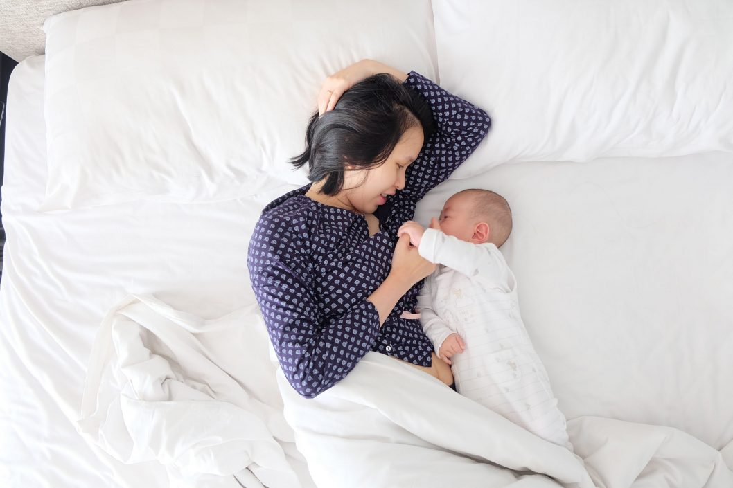 Mother has breastfeeding struggles while laying in bed with baby.