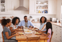 Family with teens sits at their dinner table.