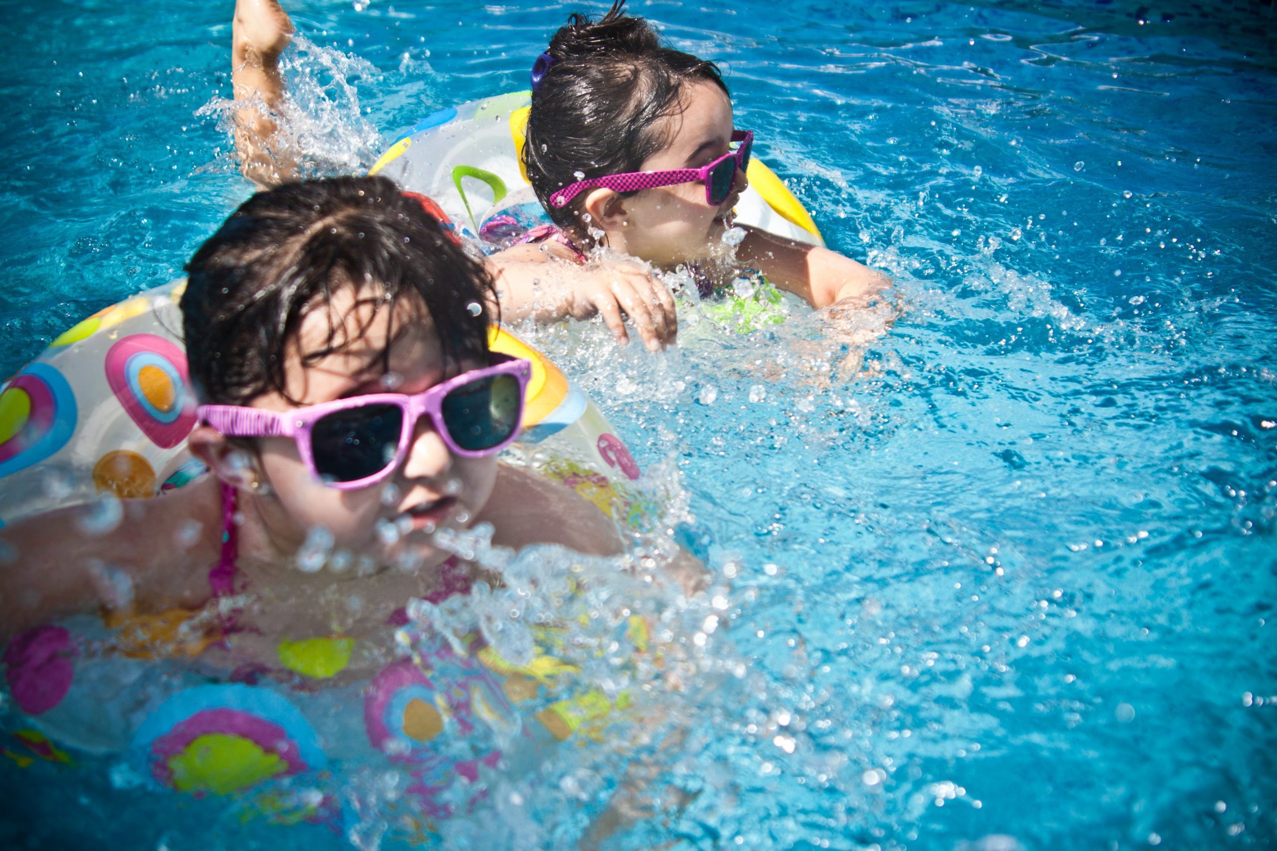 Kids float in the pool wearing sunglasses.