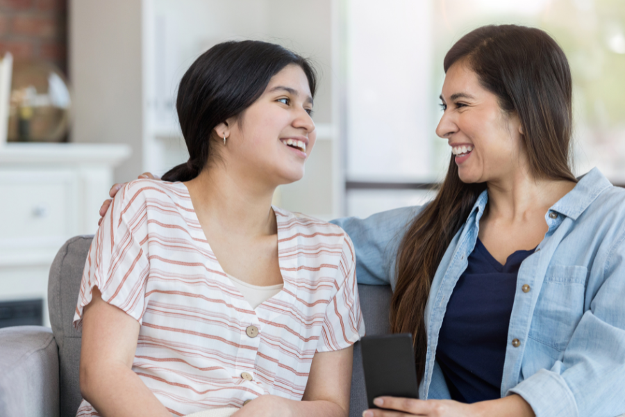 Mom and tween daughter talk and laugh together.