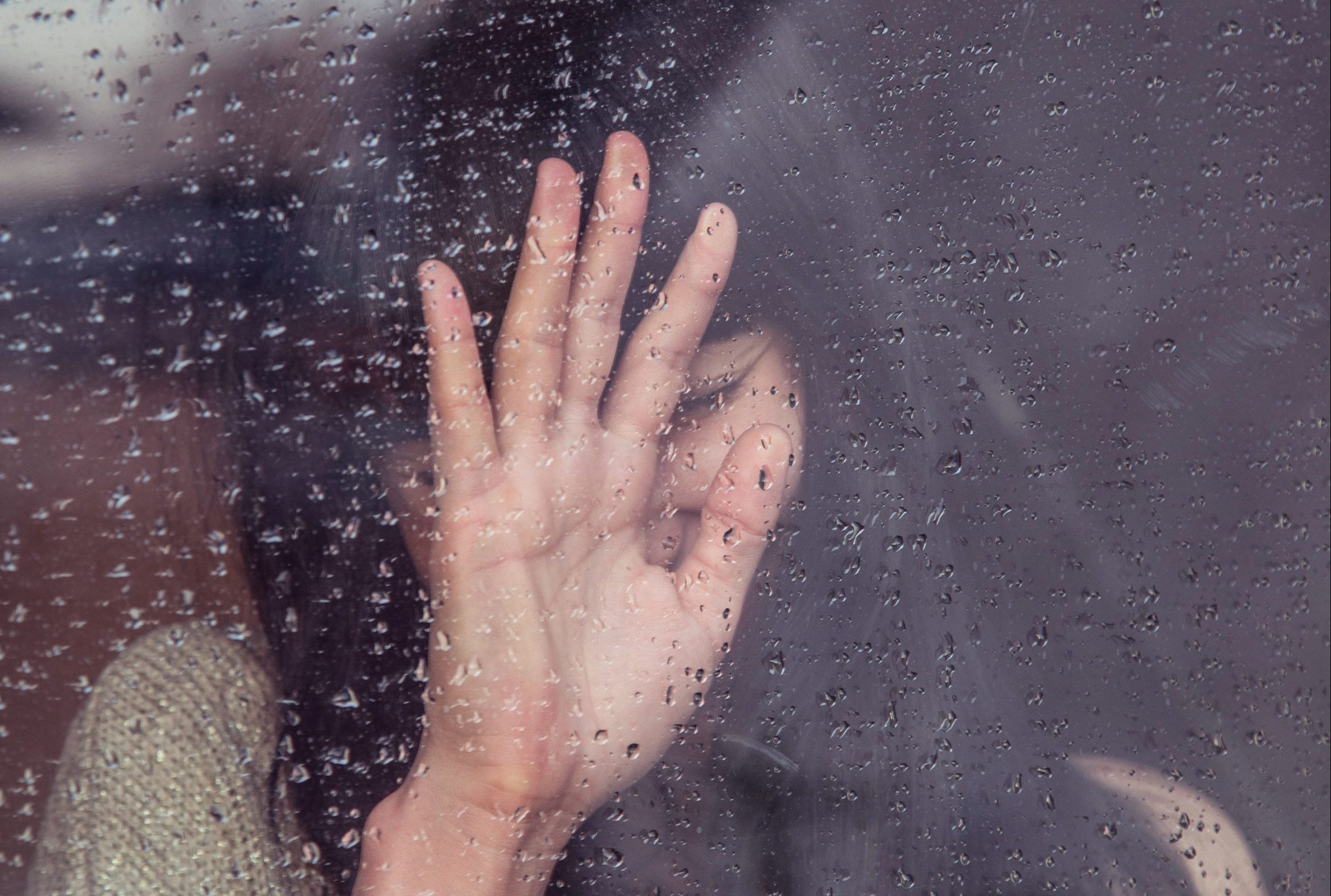 Sad woman looks out window on a rainy day.