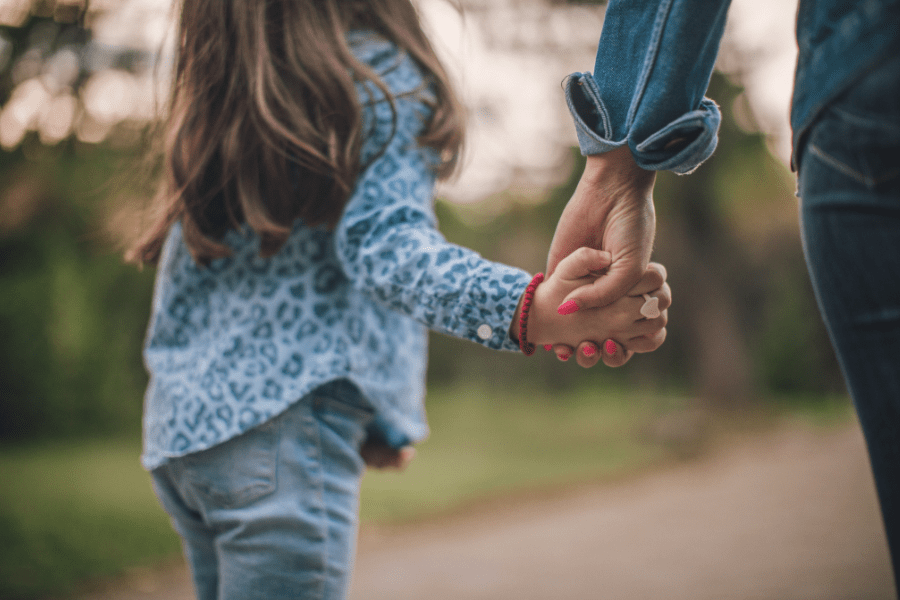 Mother with pink nails holds daughter's hands