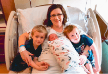 mom with newborn and children in hospital bed