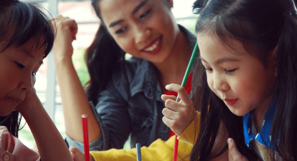 mom or teacher helping two girls with schoolwork