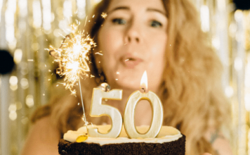 woman blowing out birthday 5-0 birthday candles, best things about turning 50