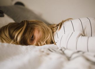 woman lying face down on bed, managing pandemic trauma