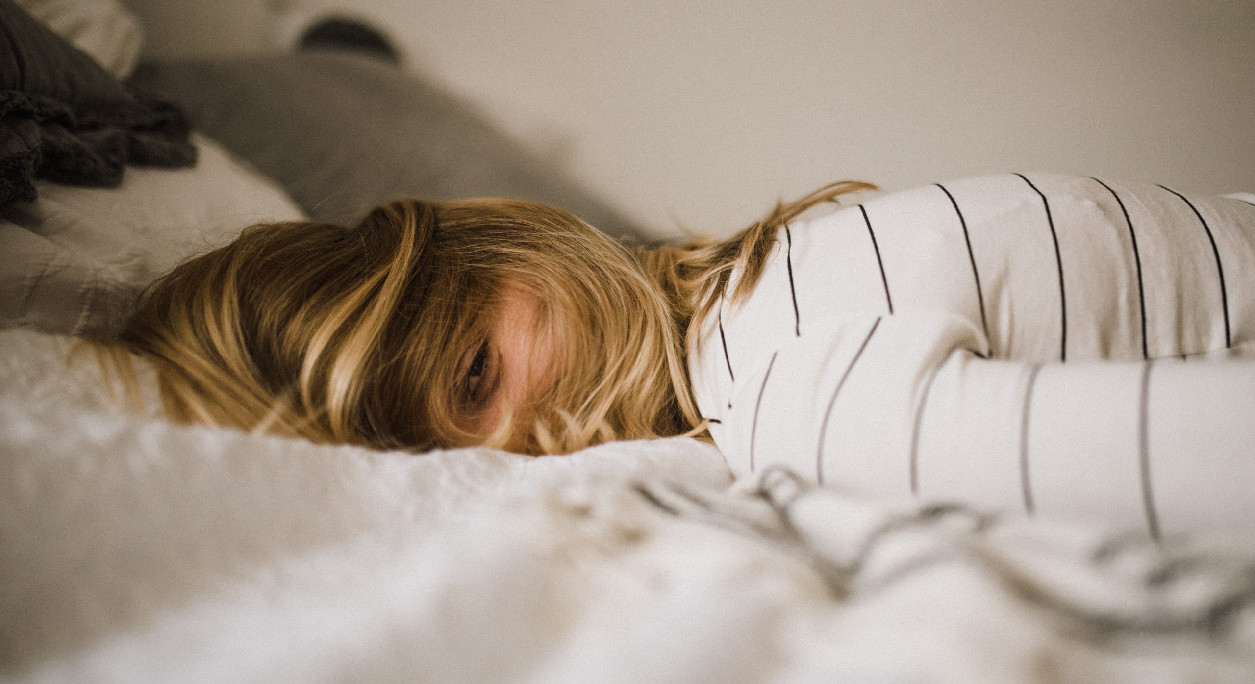 woman lying face down on bed, managing pandemic trauma