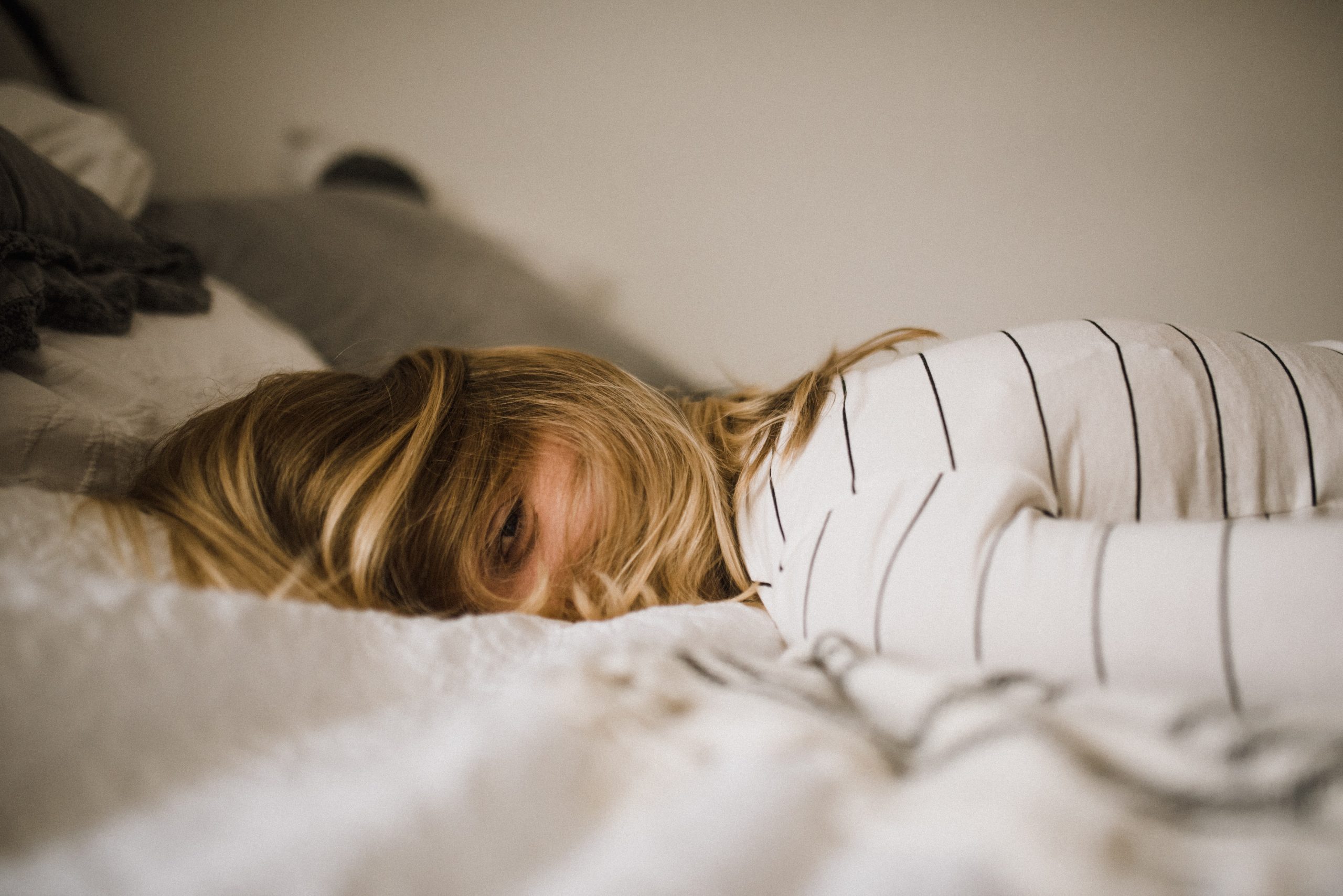 woman lying face down on bed, managing pandemic trauma