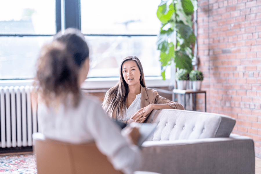 Woman in therapy sits on couch speaking to therapist.