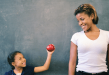 Child gives an apple to her teacher for a back-to-school teacher gift.