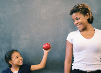 Child gives an apple to her teacher for a back-to-school teacher gift.