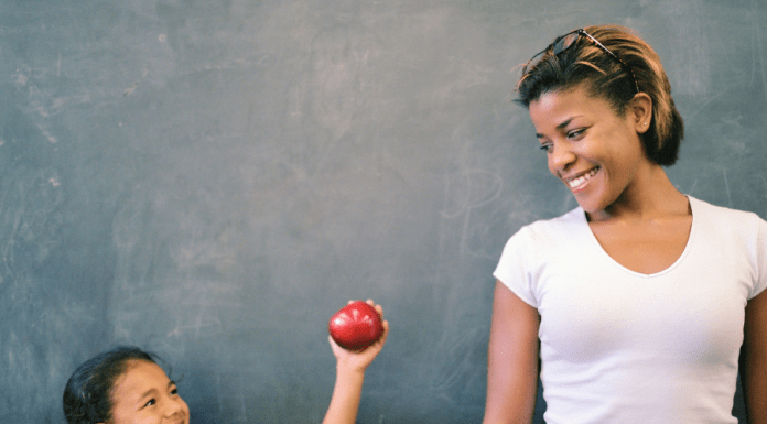 Child gives an apple to her teacher for a back-to-school teacher gift.