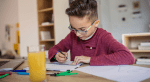 middle grade boy working on schoolwork at a table at home