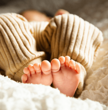 Close up on feet of baby laying on a fluffy pad