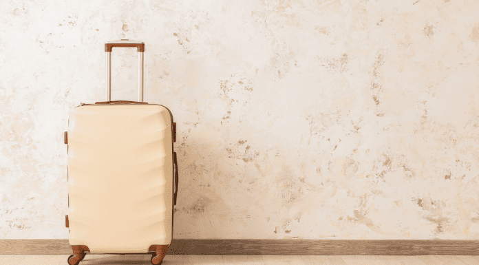 A beige carry-on suitcase against wall.