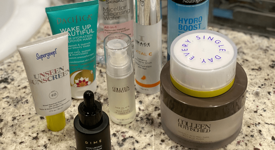 Several skincare products sitting on a bathroom counter, including sunscreen, serums, balm, moisturizer