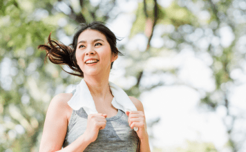 A woman exercises with a towel around her neck.