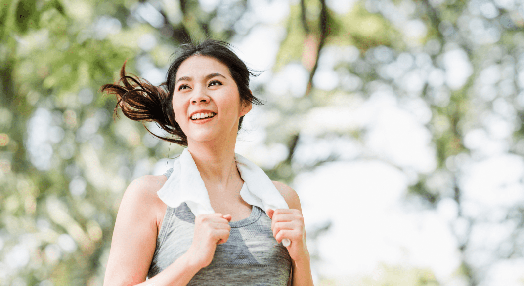 A woman exercises with a towel around her neck.