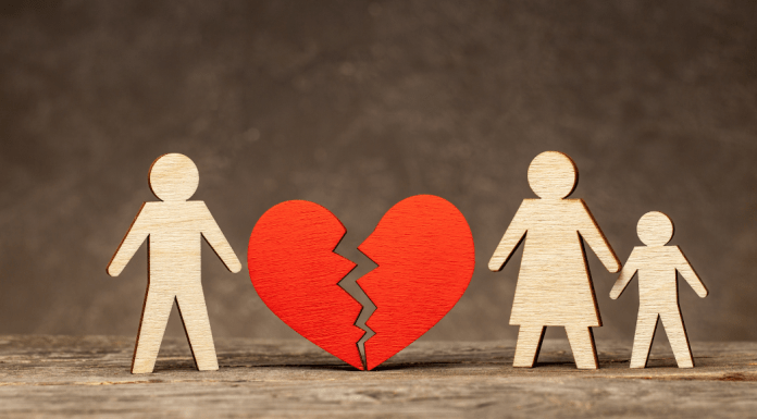 Wooden cutouts of a father, mother and child, with a broken heart between the dad and family.