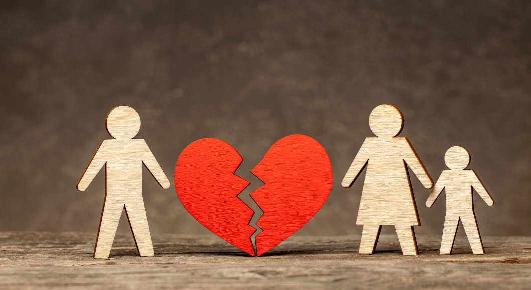 Wooden cutouts of a father, mother and child, with a broken heart between the dad and family.