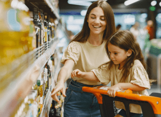 A mom points out grocery store prices to her daughter who sits in a cart.