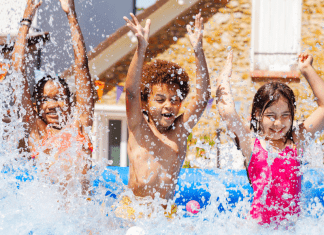 Three kids splash in a pool outside.