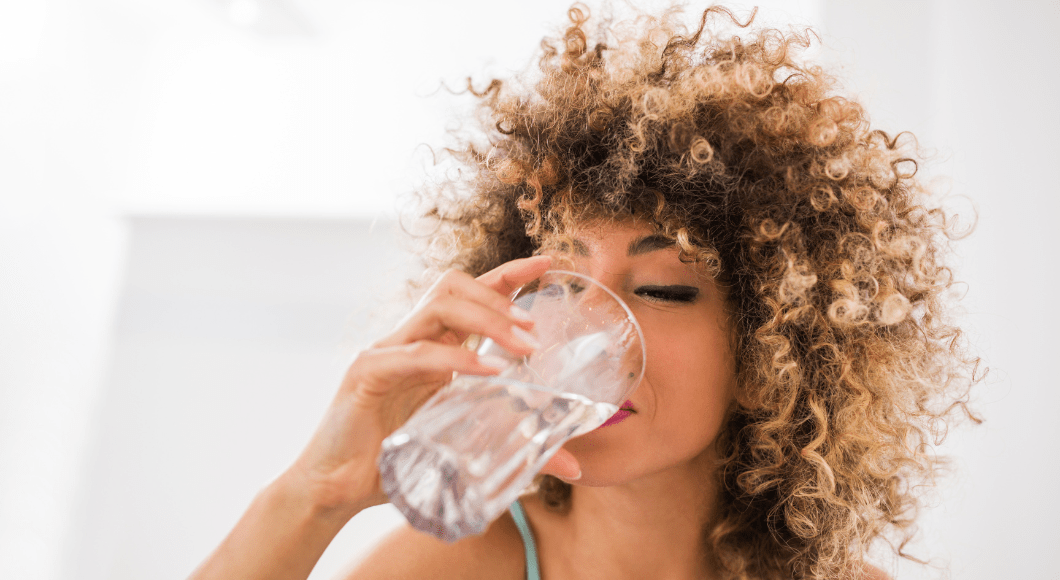 A woman drinks a glass of water