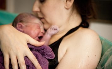 mother and baby in tub after natural birth in birthing center