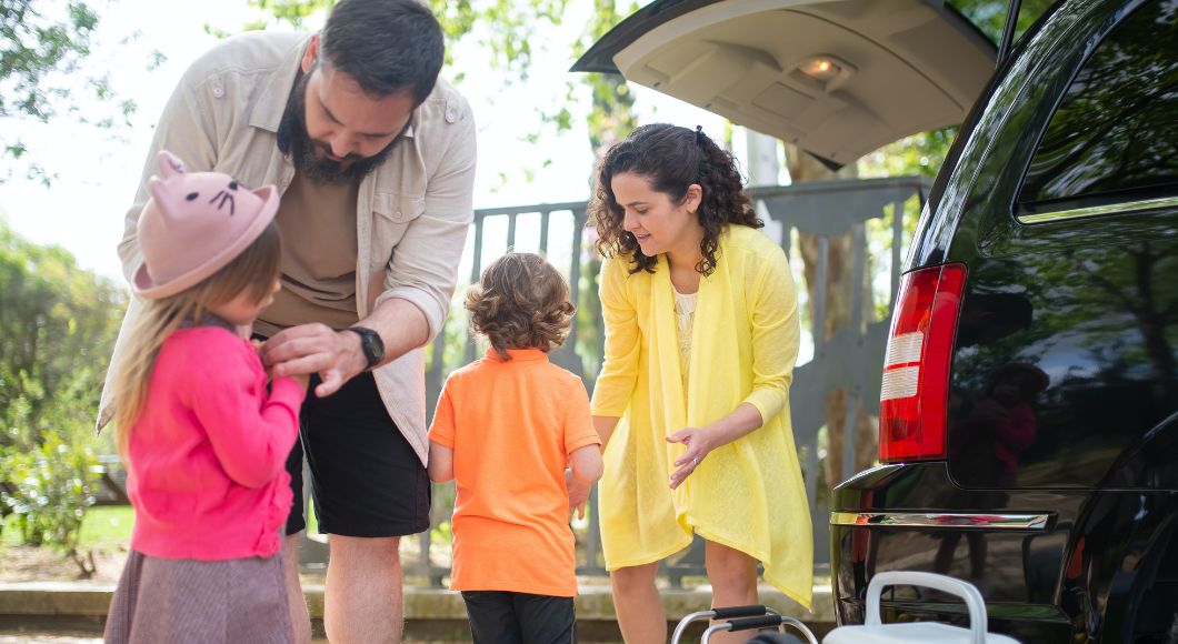 A family packs up belongings into the back of a minivan.