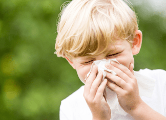 A child sneezes into a tissue.