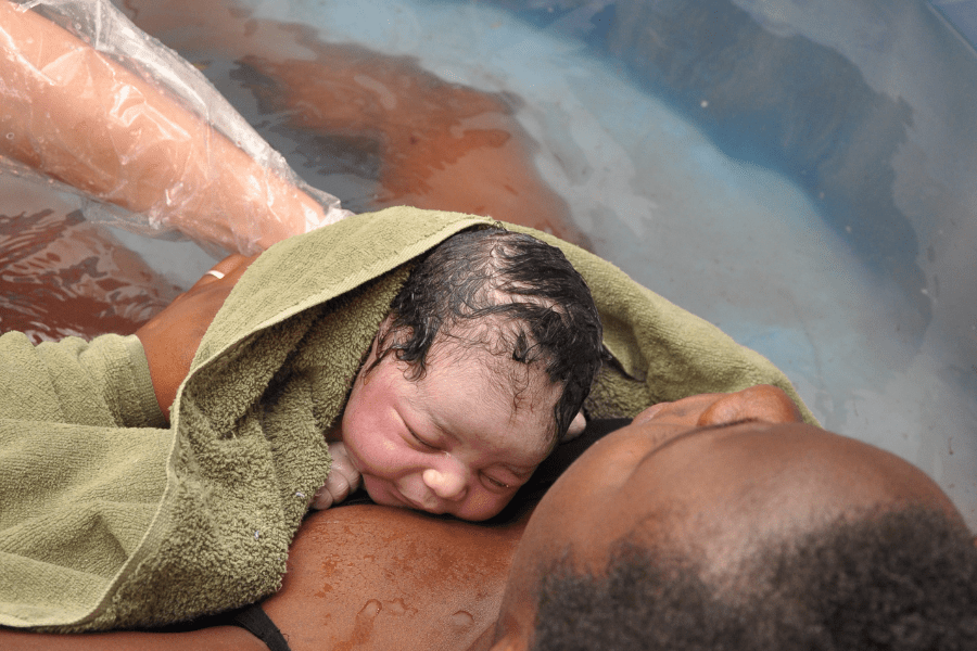 Baby lays on mom's chest right after birth in a birthing tub at a birthing center