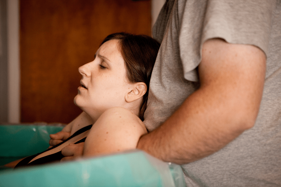 Husband soothes mom as she labors in a birthing tub at a birthing center