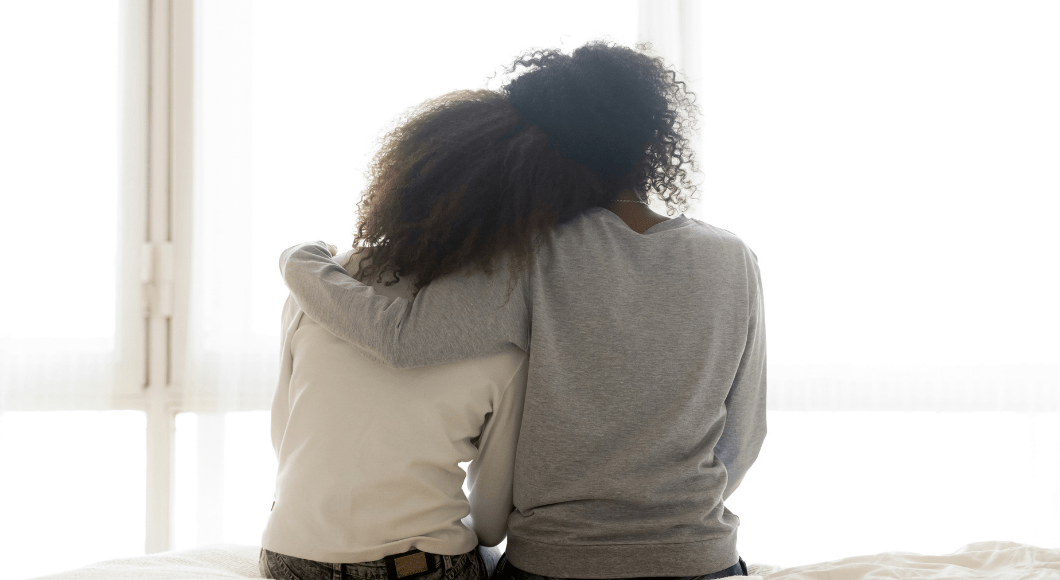 A parent gives her daughter a side hug.