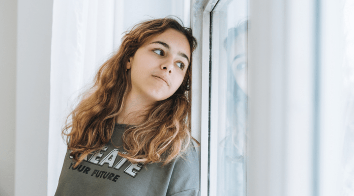 A teen looks out the window.