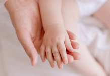 A baby rests her hand in mom's palm.