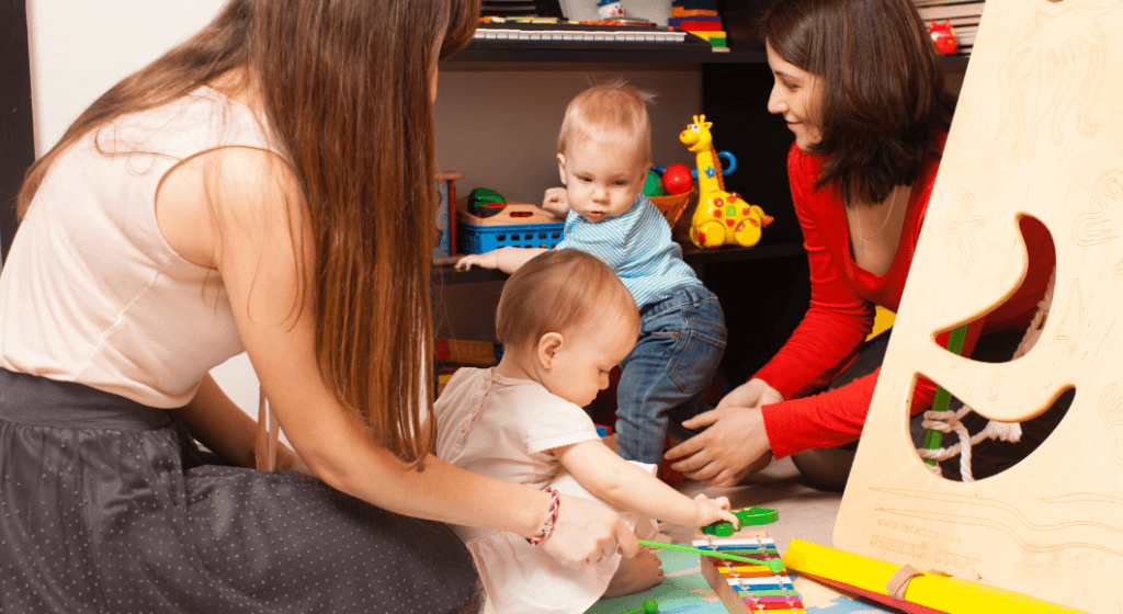 Two moms watch their toddlers play with toys. 