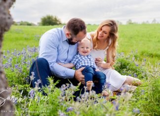 Family sits for a portrait in a patch of Texas bluebonnets.