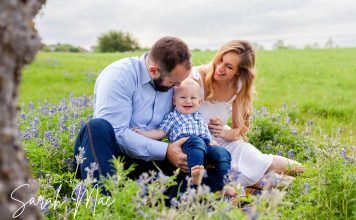 Family sits for a portrait in a patch of Texas bluebonnets.