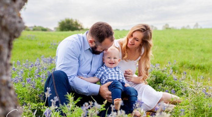 Family sits for a portrait in a patch of Texas bluebonnets.