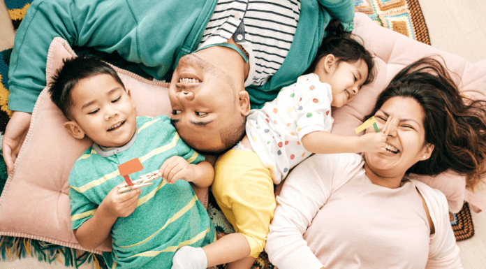 A happy family laughs together on the floor.