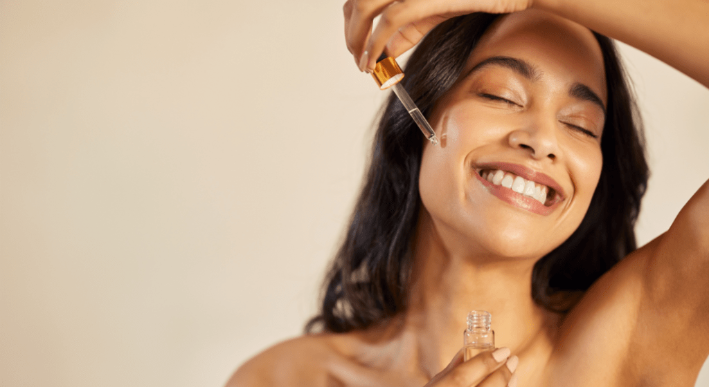 A woman applies serum to her face.