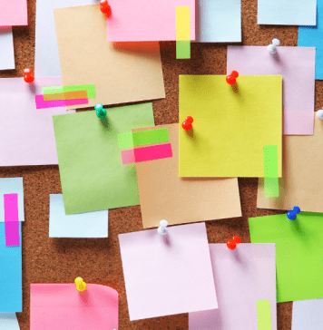 A bulletin board covered in colorful sticky notes, washi tape, and thumbtacks.